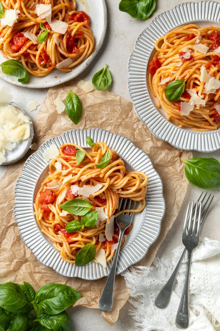 Three plates of spaghetti al pomodoro with fresh basil and parmesan.