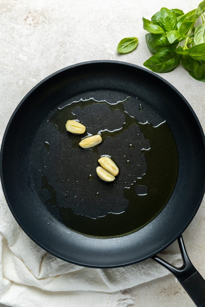 Two halved cloves of garlic frying in olive oil.