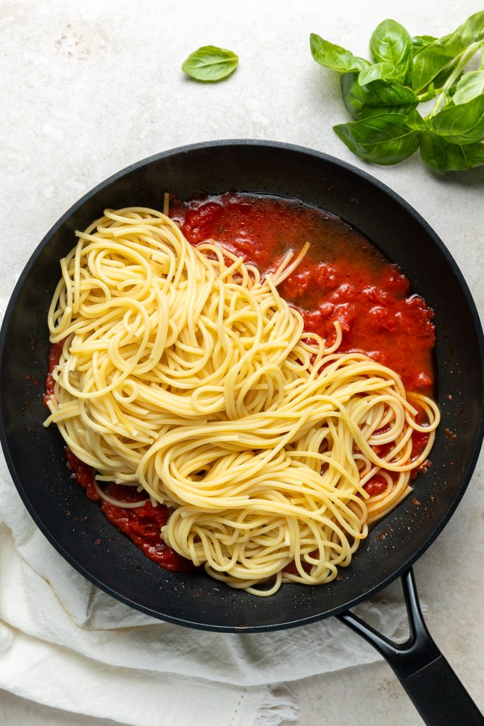 Cooked spaghetti and pasta cooking water added to the tomato sauce.