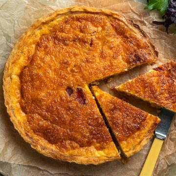 A quiche lorraine with two slices cut out of it.