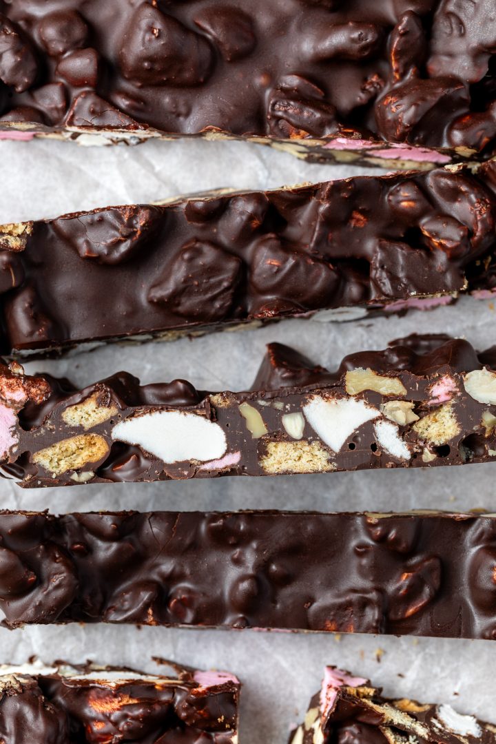 Close up of rocky road, one piece on its side to show the marshmallows, biscuits pieces and nuts.