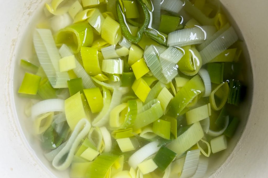 The cooked leeks in their stock in a saucepan.