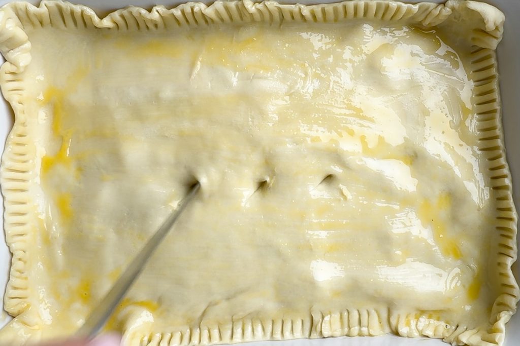 A sheet of puff pastry placed over the filling, brushed with beaten egg and a sharp knife making holes in the top to let out the steam.