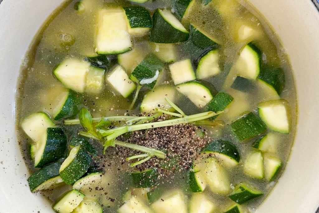 Stock, basil stalks and seasoning added to the saucepan.