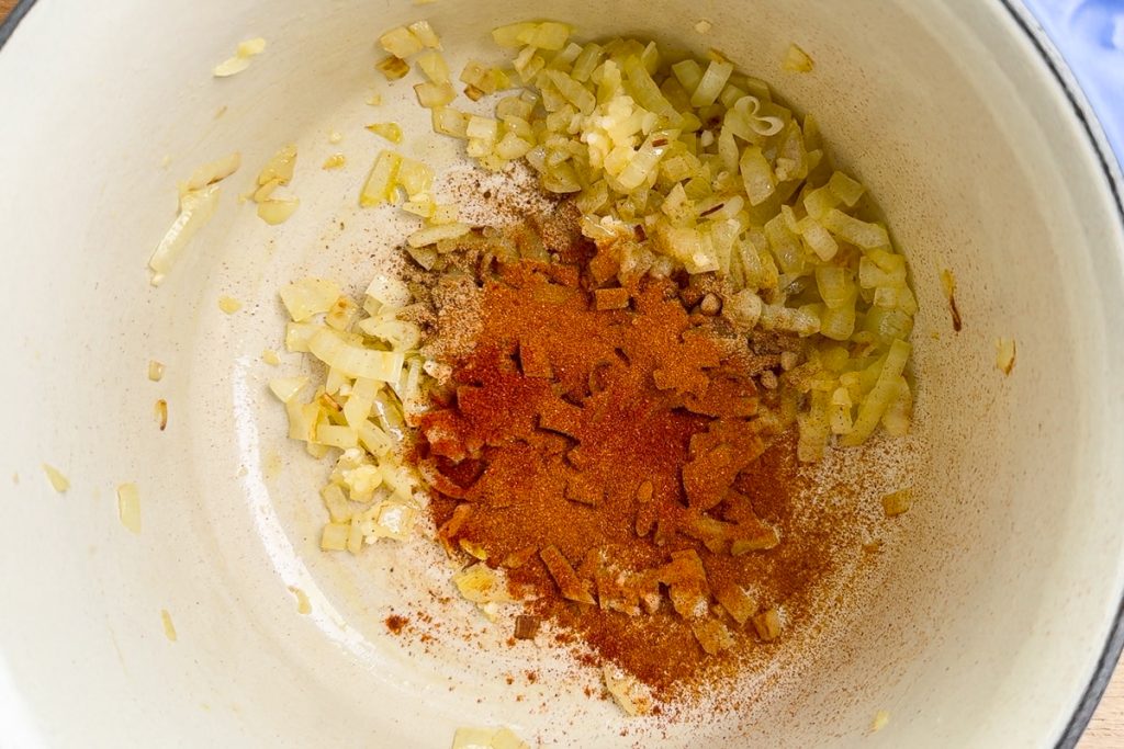 The spices added to the softened onion in the saucepan.