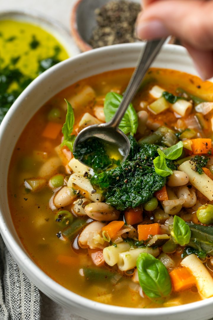 Pistou being spooned on top of a bowl of vegetable soup.