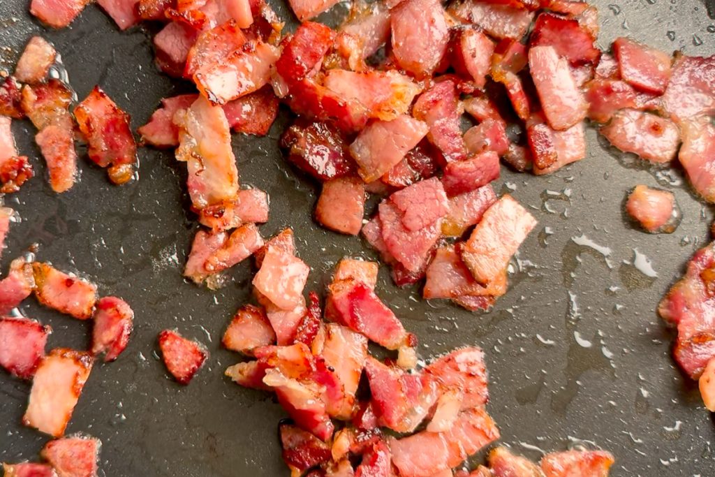 Bacon fried until golden in a pan.