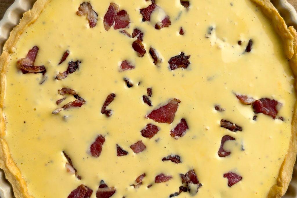 The egg custard and crispy bacon in the pastry case ready to go in the oven.