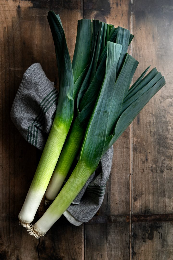 A bunch of fresh leeks on a wooden background.