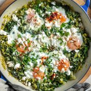 A pan of baked eggs with silverbeet and leeks, sprinkled with feta.
