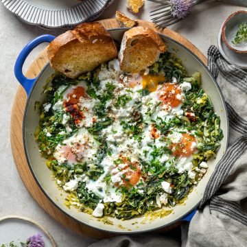 A pan of baked eggs with silverbeet and leeks sprinkled with feta and smoked paprika.