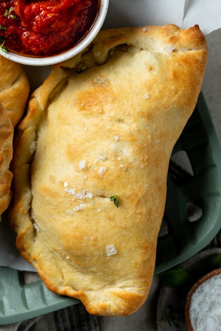 Close up of a baked calzone topped with flaky salt.
