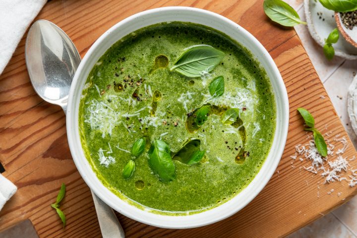 A bowl of silverbeet soup sprinkled with grated parmesan cheese and fresh basil.