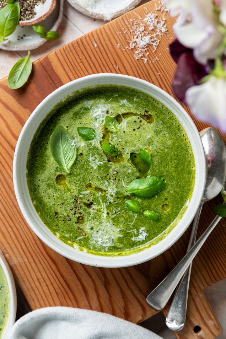 A bowl of silverbeet soup on a wooden board with a sprinkling of parmesan over it.