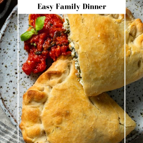 Calzone cut in half on plate, served with tomato sauce.