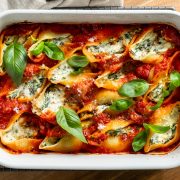 Baked silverbeet and ricotta stuffed shells in a baking dish sprinkled with fresh basil.