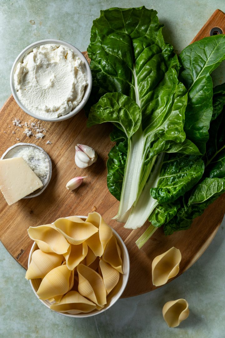 The ingredients needed to make the stuffed shells recipe on a wooden board.