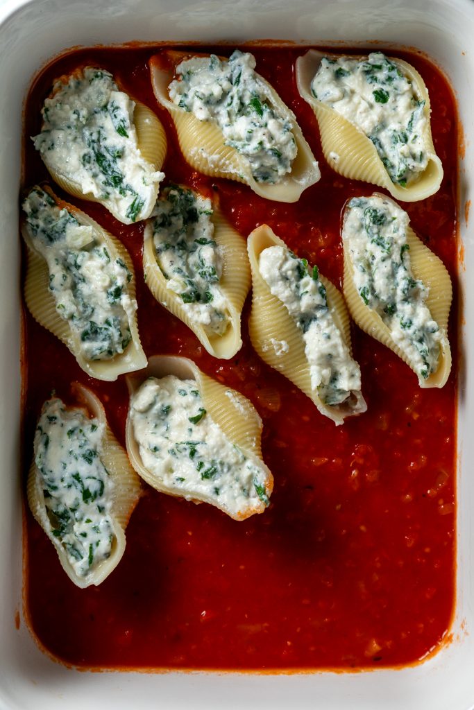 Two thirds of the pasta shells stuffed and put in the baking dish on top of tomato sauce.