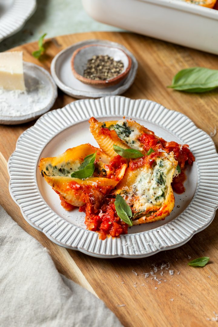 A serving of the stuffed pasta shells on a plate, the baking dish just visible behind.