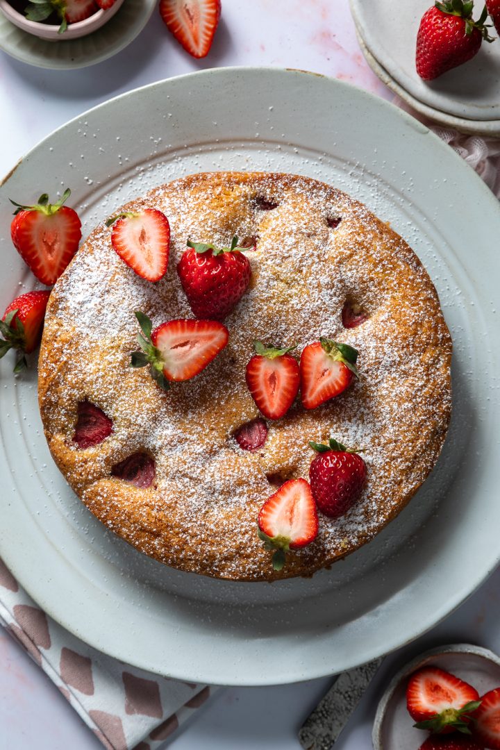 The baked strawberry cake topped with halved fresh strawberries.