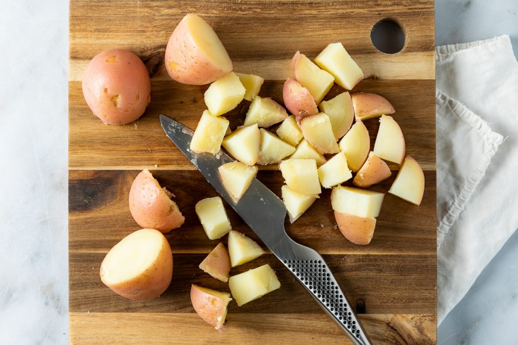 The cooked potatoes being chopped into bite size pieces.