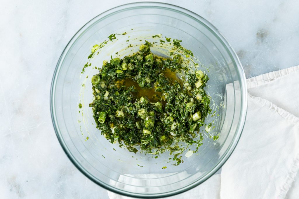 The herb vinaigrette mixed together in a glass bowl.