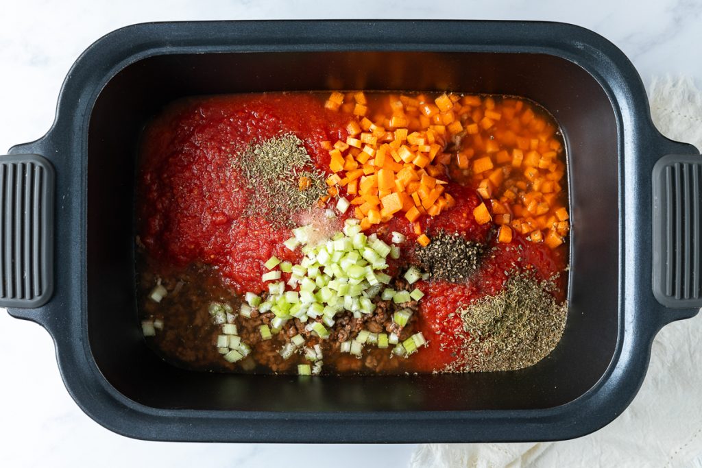 Chopped vegetables, tinned tomatoes, stock and seasonings in the slow cooker.