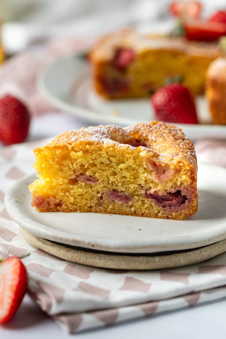 A side view of a slice of strawberry cake on a plate.