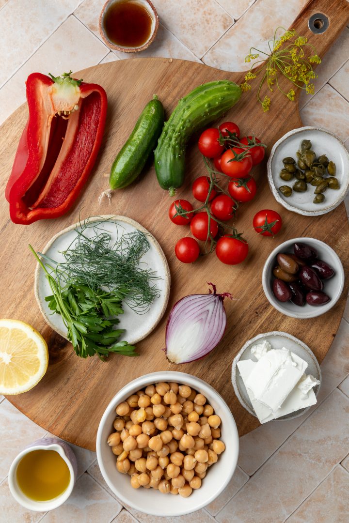 Ingredients needed to make the salad on a wooden board.