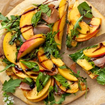 Peach and prosciutto pizza with two slices cut from it.
