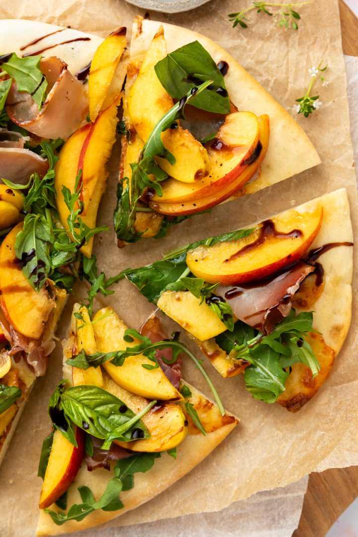 Close up of three wedges of the pizza topped with fresh peaches and prosciutto.