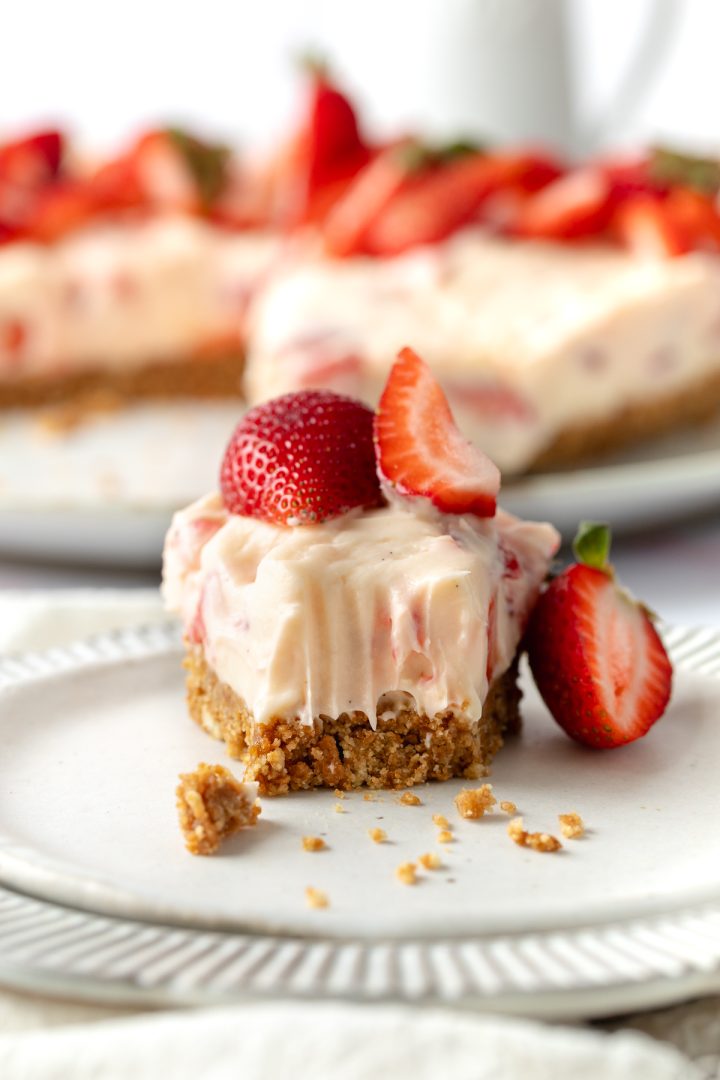A slice of cheesecake on a plate with a forkful taken out, to show the texture.