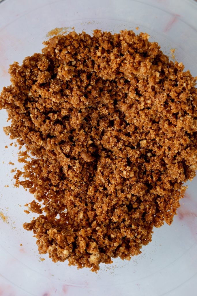 The Digestive biscuit and Biscoff biscuit crumbs mixed with melted butter in a bowl.