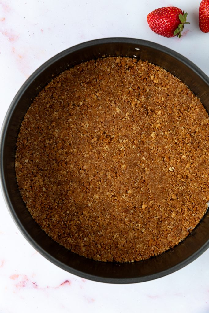 The biscuit crumbs pressed into the base of a lined tin.