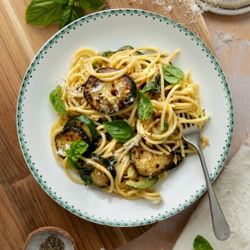 A bowl of courgette pasta with a fork holding a portion of spaghetti.