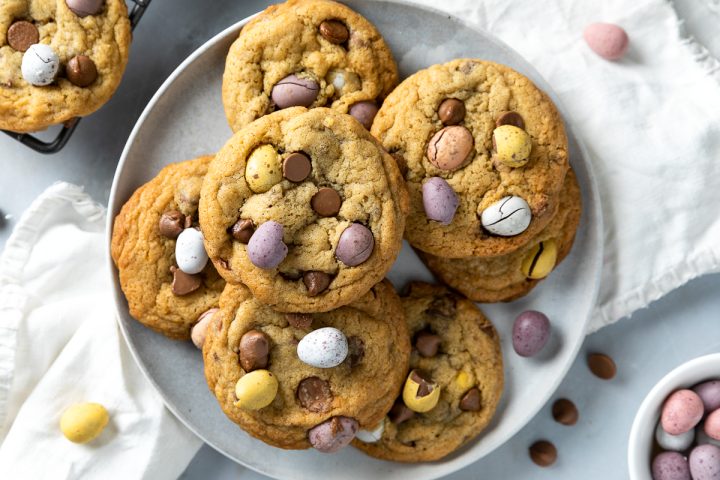 A plate of mini egg cookies, with chocolate mini eggs scattered around the plate.