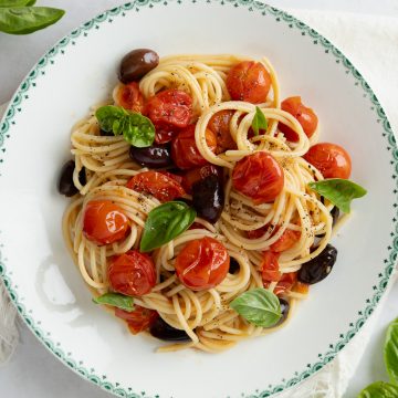 Roasted cherry tomato pasta in a bowl, sprinkled with fresh pasta.