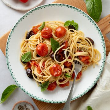 A bowl of roasted cherry tomato pasta sprinkled with basil.