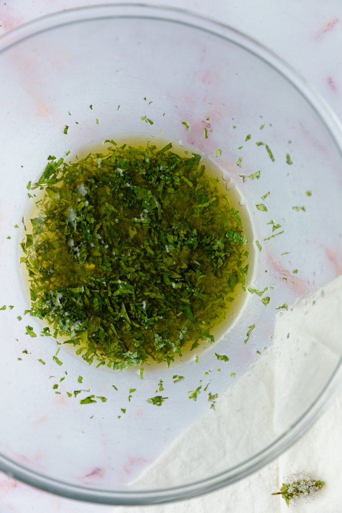 The olive oil and vinegar mixed with the mint and garlic in a bowl.