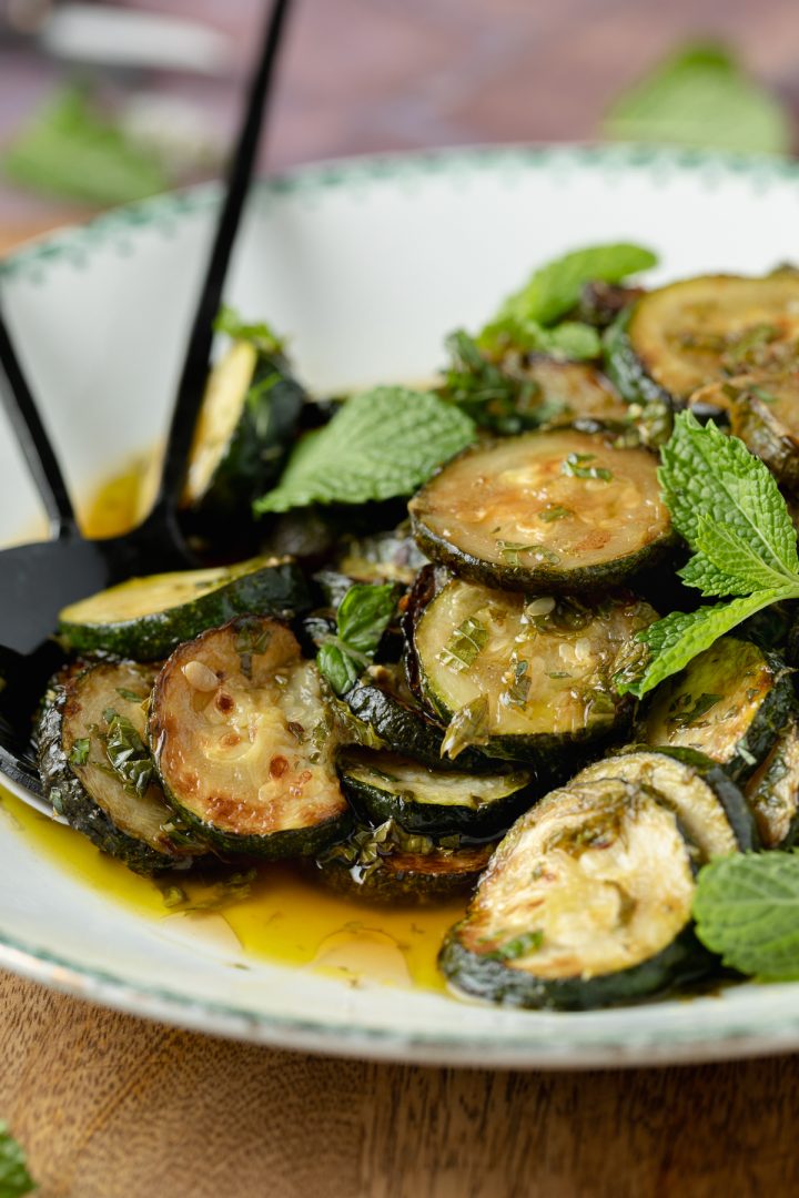 Close up of the marinated zucchini with a serving spoon.