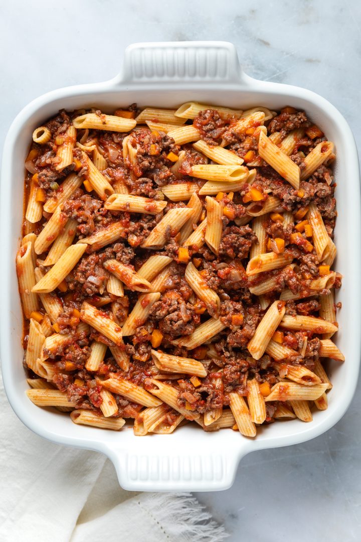 The bolognese sauce and pasta in a baking dish.