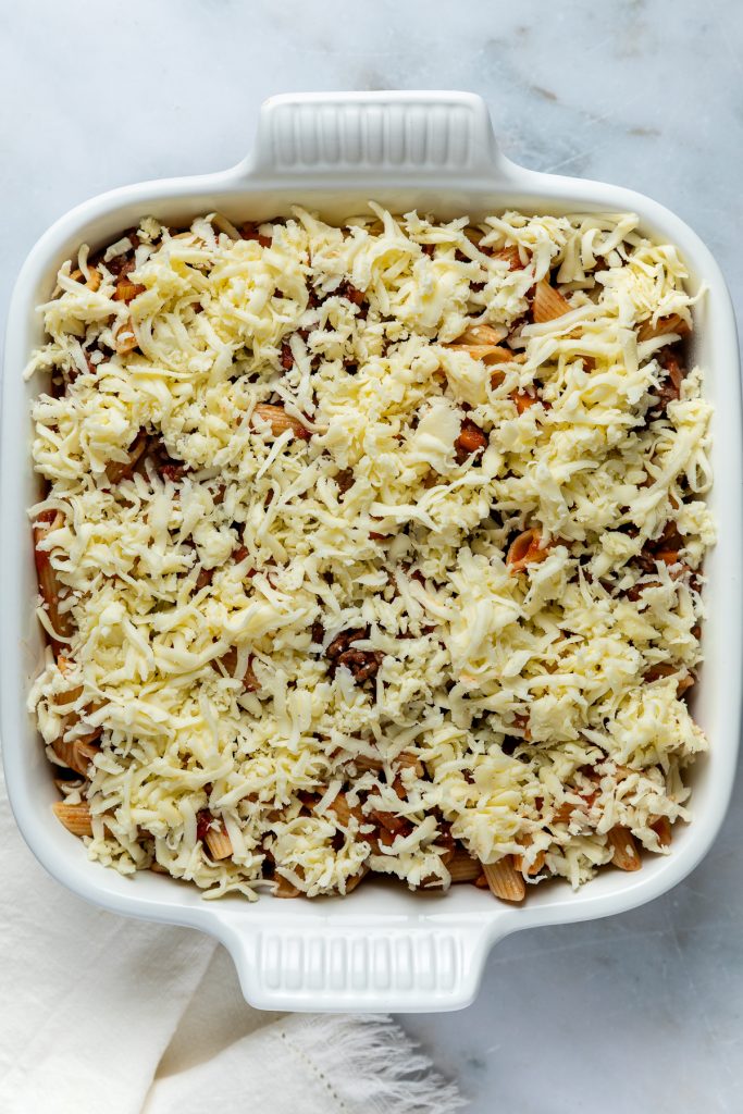 The pasta bake sprinkled with grated cheese ready to go into the oven.