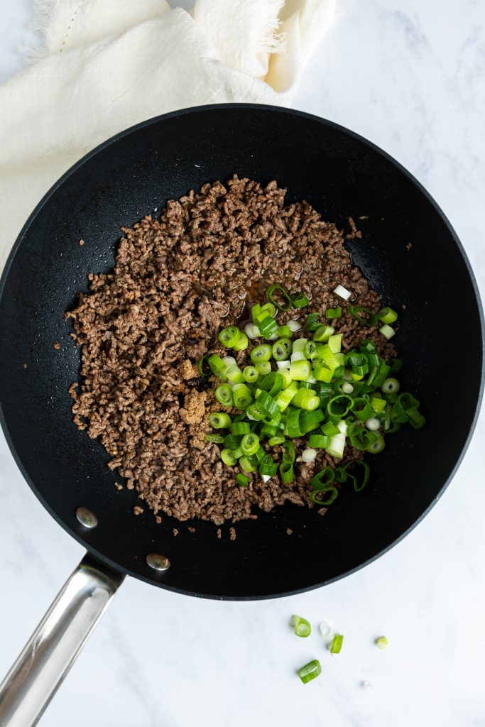 Sliced spring onions, soy sauce and water added to the pan.