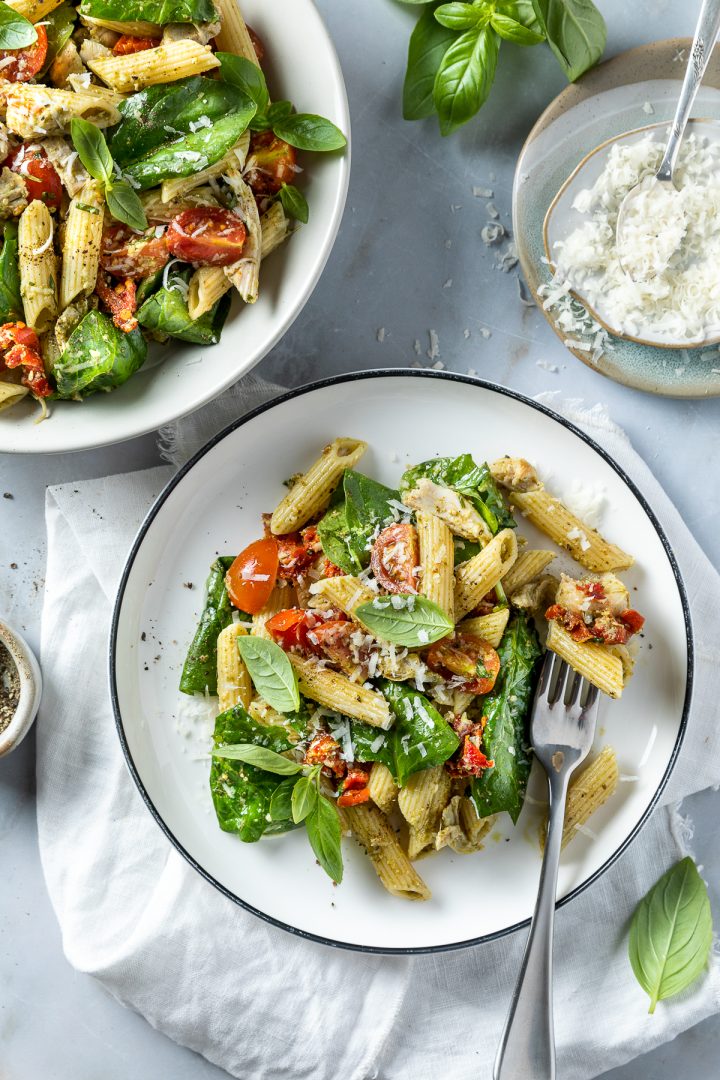 A plate of pasta with chicken and pesto.