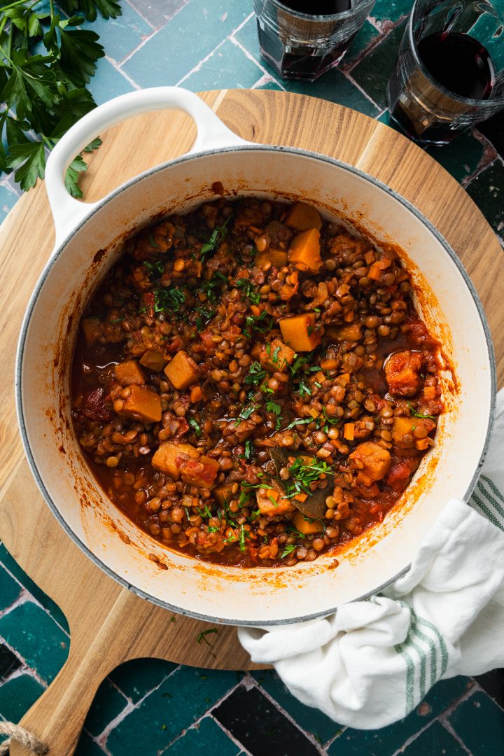 A cast iron pan of the cooked lentil ragu sprinkled with parsley ready to serve.