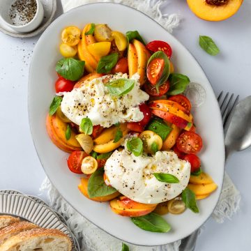 Burrata and peach salad on a serving platter ready to serve.