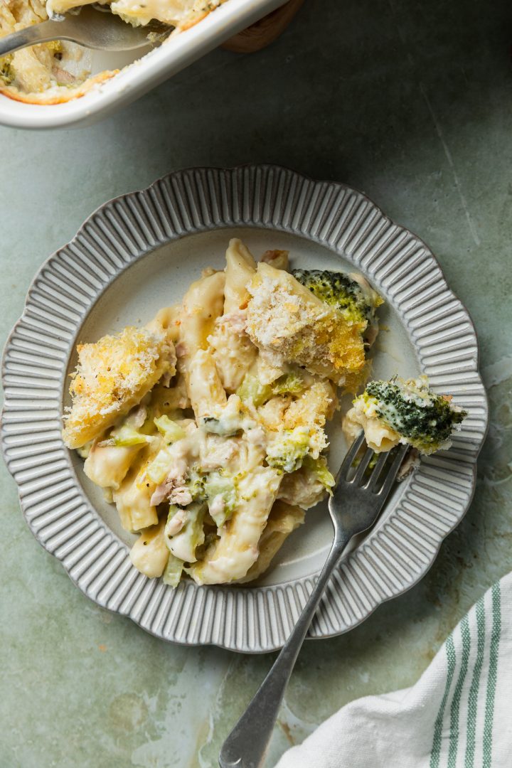 A plate of tuna broccoli pasta with a fork holding a piece of broccoli.
