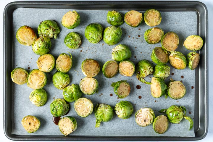 The halved Brussels sprouts mixed with brown sugar and vinegar and placed on a lined baking tray.