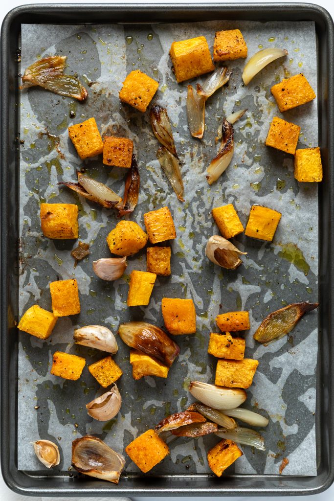 Roasted butternut squash, garlic and shallot on a tray.