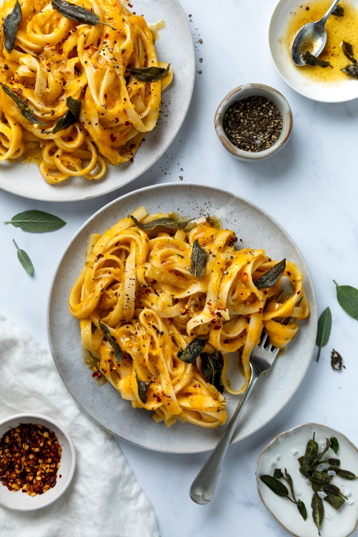Two plates of pasta with crispy sage and brown butter.